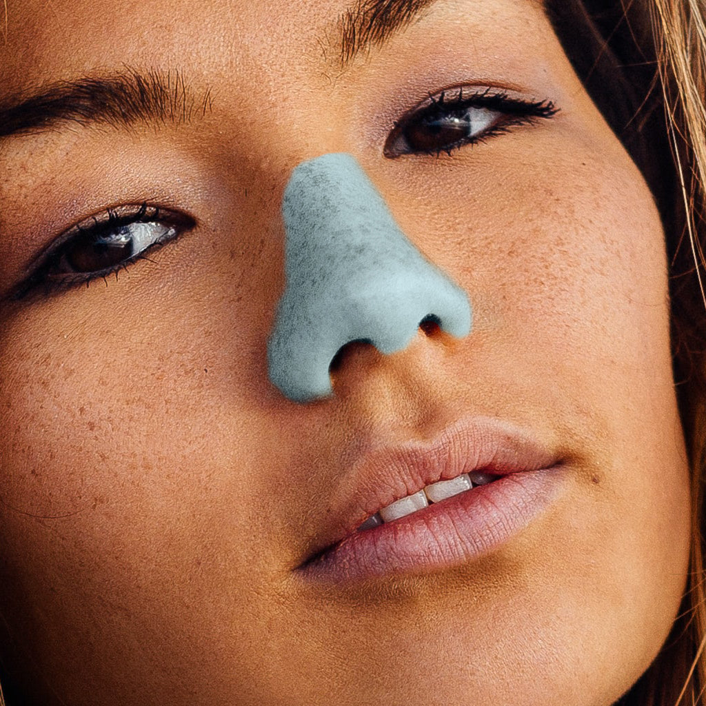 up-close picture of a person's face with clear blue sky Nözscreen on their nose